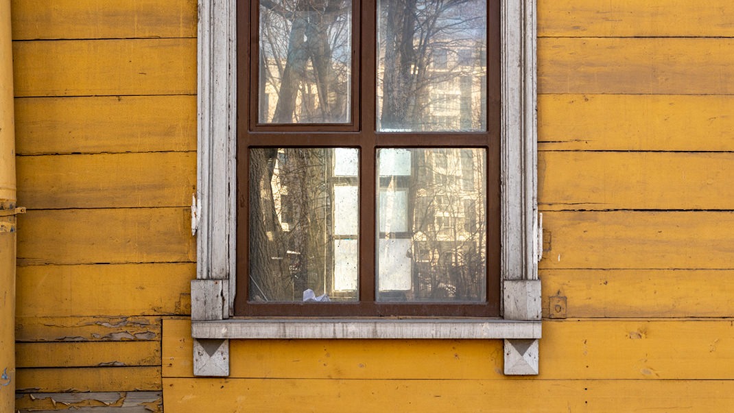 Сквозь пыльные стёкла окон здания видно лишь запустение