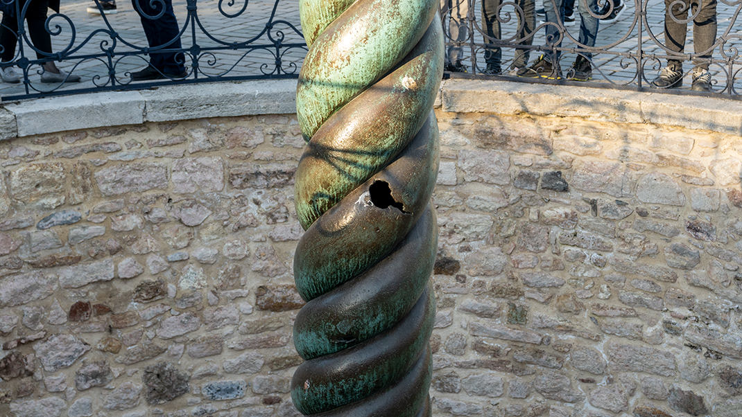 Первоначально в навершии монумента располагалось три змеиных головы с золотым котлом